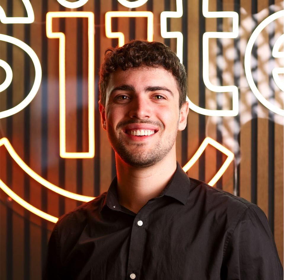 Man smiling, neon sign background.