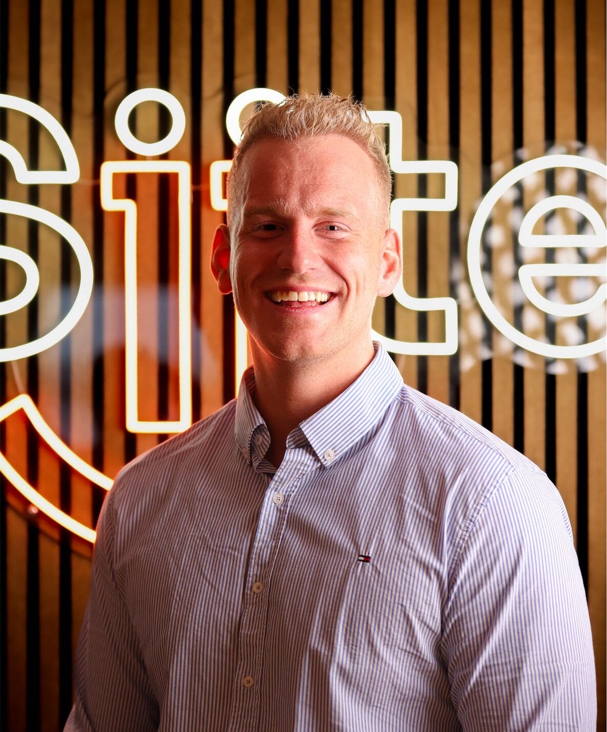 Smiling businessman in front of neon sign.